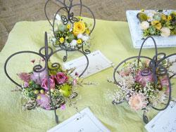 黄色とピンクに咲いたバラの鉢が3つテーブルの上に置いてある写真