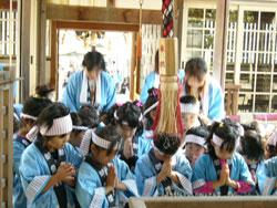 神社の拝殿でお祈りをしている子供たちの写真