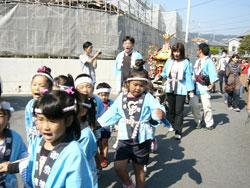 水色の法被を着て神輿を曳いている子供たちの写真