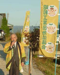 昭和工業団地と書かれたのぼりの横で黄色の法被を着た男性が話をしている写真