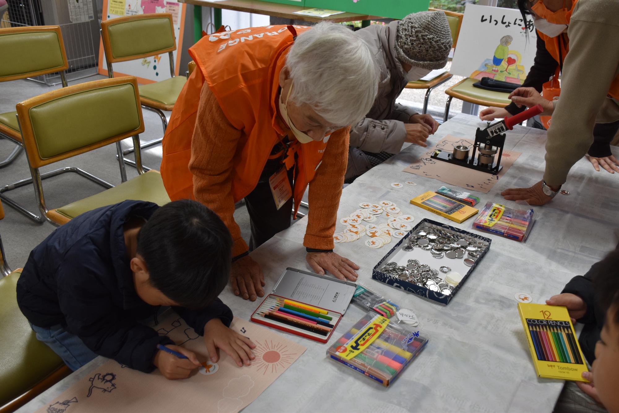 缶バッジを作る子供と指導員