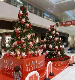 大きなクリスマスツリーが2つ並んでおり、手前で子供が見上げている写真