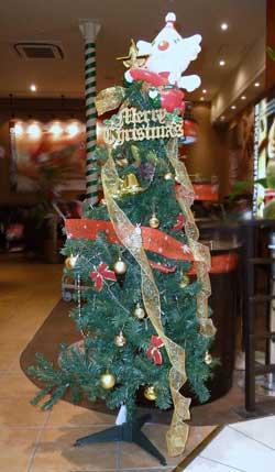 英語でメリークリスマスとモチーフに書かれた飾りと、赤とゴールドのリボンが巻き付けられているツリーの写真
