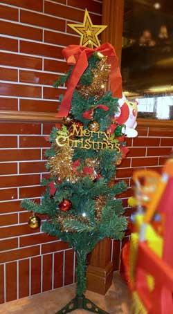 英語でメリークリスマスとモチーフに書かれた飾りと一番上に星が飾られたクリスマスツリーの写真
