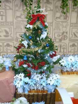 メリークリスマスと書かれたモチーフの下に赤いリボンの飾りがされている、少し大きめのクリスマスツリーの写真