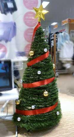 赤いリボンが3周してある、木のさきにはに金の星がついているクリスマスツリーの写真。