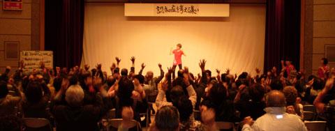 舞台上で踊っている人に向かって観客たちが手を挙げている写真