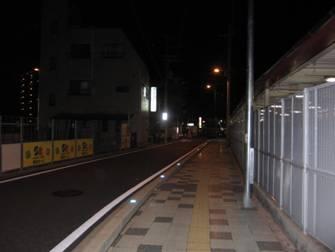 左奥に建物がある、夜の広い歩道の写真