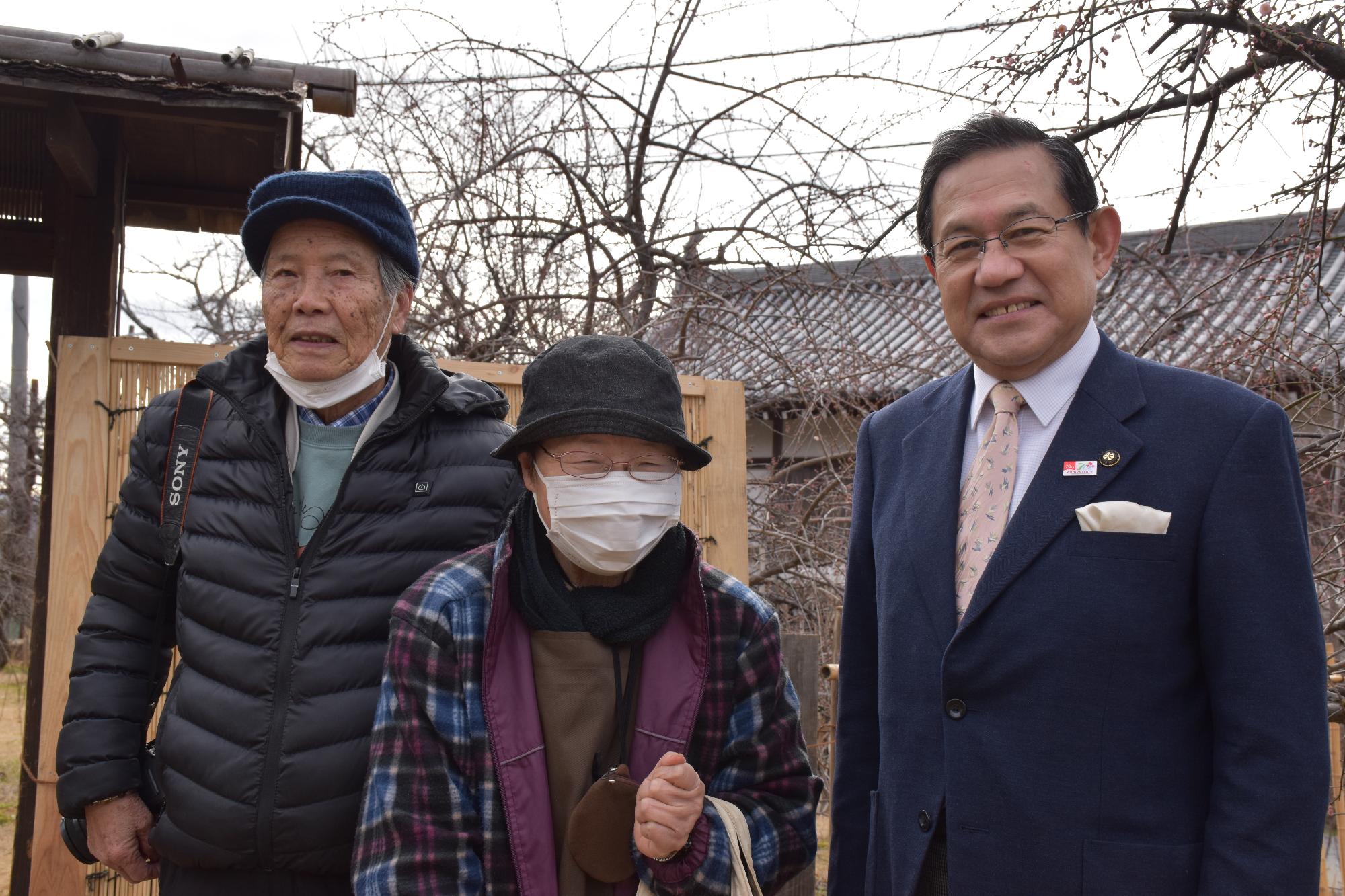 盆梅展一番乗りの女性と並ぶ市長