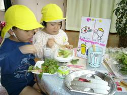 テーブルに置かれた手書きのメニューと野菜を皿に入れている子供の写真