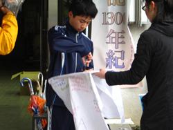 横断幕を手渡す女性と、メッセージを書く中学生ランナーの写真