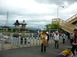 歩道橋のそばで並ぶ二つの石塔の写真