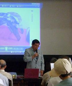 スクリーンに映し出された映像の前でマイクを持って話す上田市長の写真