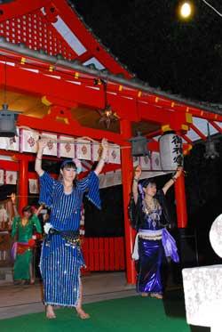 カラフルな着物を着て神社の建物の前で両手をあげて踊る3人の写真