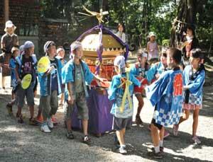 斜め前から見た法被を着てお神輿を曳いている子供たちの写真