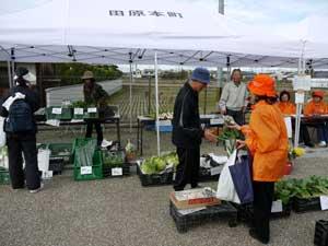 ゴール地点で地場野菜を売っている人とかっている参加者たちの写真