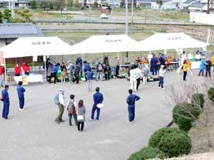 白い屋根のテントがあるスペースにまばらにいる参加者たちを黒田大塚古墳頂上からみた写真