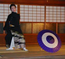 床に置かれた和傘の横で踊っている女性の写真
