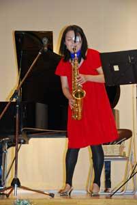 赤いドレスでサックスフォーンを演奏している女性の写真