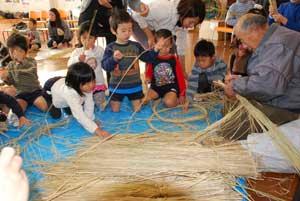 床に広げられた稲わらを子供たちが見ている写真