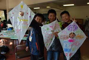 男の子が3人並び作った凧を掲げている写真