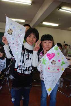 女の子が2人並び作った凧を掲げている写真