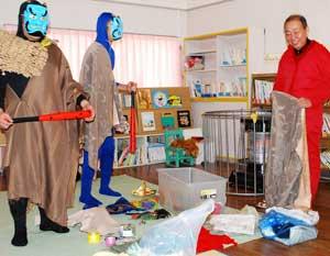左に2人の青いお面の鬼が立っており、右に赤いス作業着の男のひとが笑っている写真。