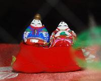小さい赤座布団に小さいひな人形が2つ飾られた写真