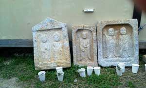 発掘された3枚の石仏が地面に立てかけられている写真