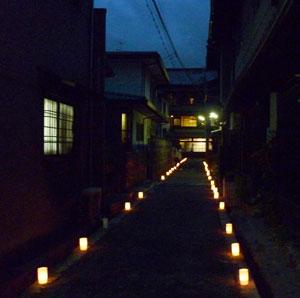 洞泉寺町の両側に家があり、薄暗い中、小さいライトが道沿いに並んでいる写真