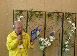黄色い洋服を着た男性が、紫の紙を持って立っている写真