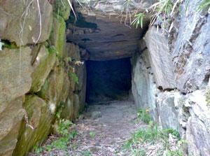 古墳内部の暗い石室へと続く石組みの通路を正面から捉えた写真