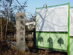 石碑の横に工事の緑と白のフェンスがある写真