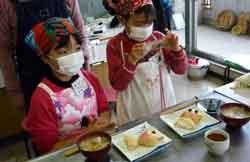女の子二人が金魚型の稲荷寿司を携帯電話で撮影している写真