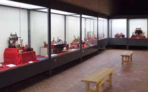 椅子が中央にあり、側面にガラス張りの展示がある、季節展示室内の写真