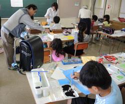 子供が教室の中で、机毎に絵を書く作業をしている写真