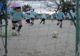 屋外でサッカーをする子どもたちの写真