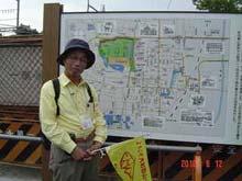 観光ボランティアガイドの山下氏とその後ろにある周辺地図の写真
