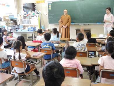 教室内で講師である僧侶の男性に質問する子供たちの写真