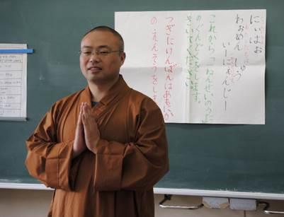 合掌し、中国語の挨拶を披露する僧侶の男性の写真
