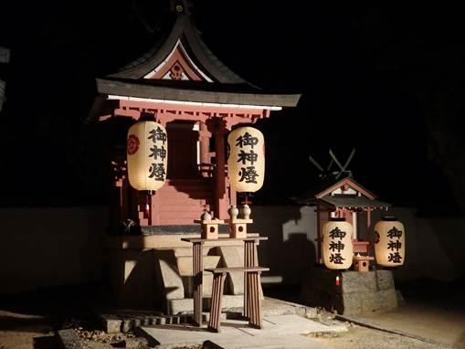 黒い屋根、赤い壁に2つ提灯のついた大小並んだ杵築神社の写真