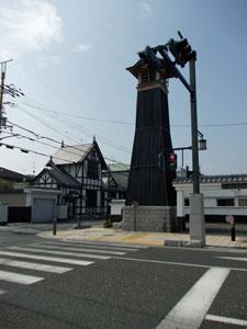 横断歩道の後ろに木造の背が高い塔がある写真