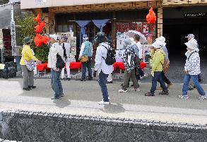 赤い金魚の飾りで彩られた店を見物する参加者たちの写真