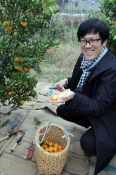 収穫した大和橘の実を笑顔で掌に載せる男性の写真