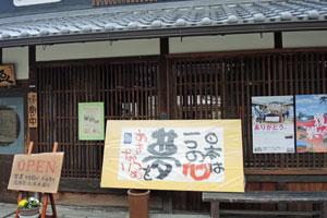 瓦屋根の下に、「日本は一つの心 夢をあきらめない」と筆で書かれたボードが展示されている写真