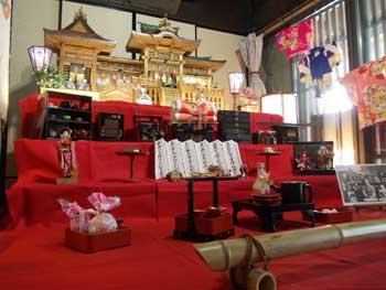 金色の「御殿雛」を中心に供え物や多数の人形が飾られた様子の写真