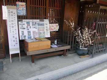 昔ながらの日本家屋の軒下に飾られた梅の木と看板の写真