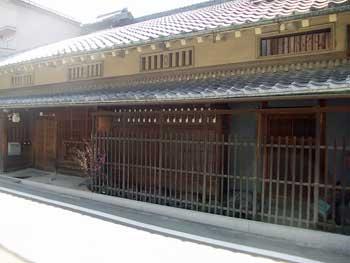 陽光に垂らされる瓦と土壁、木材で形作られた日本家屋の写真