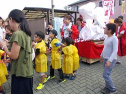 黄色い法被を着て金魚ねぶたを担ぐ子供たちの写真