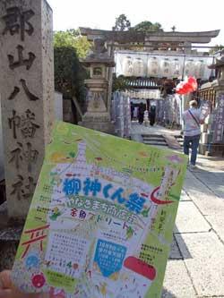 鳥居と石碑を背景に映る柳神くん祭のポスターの写真